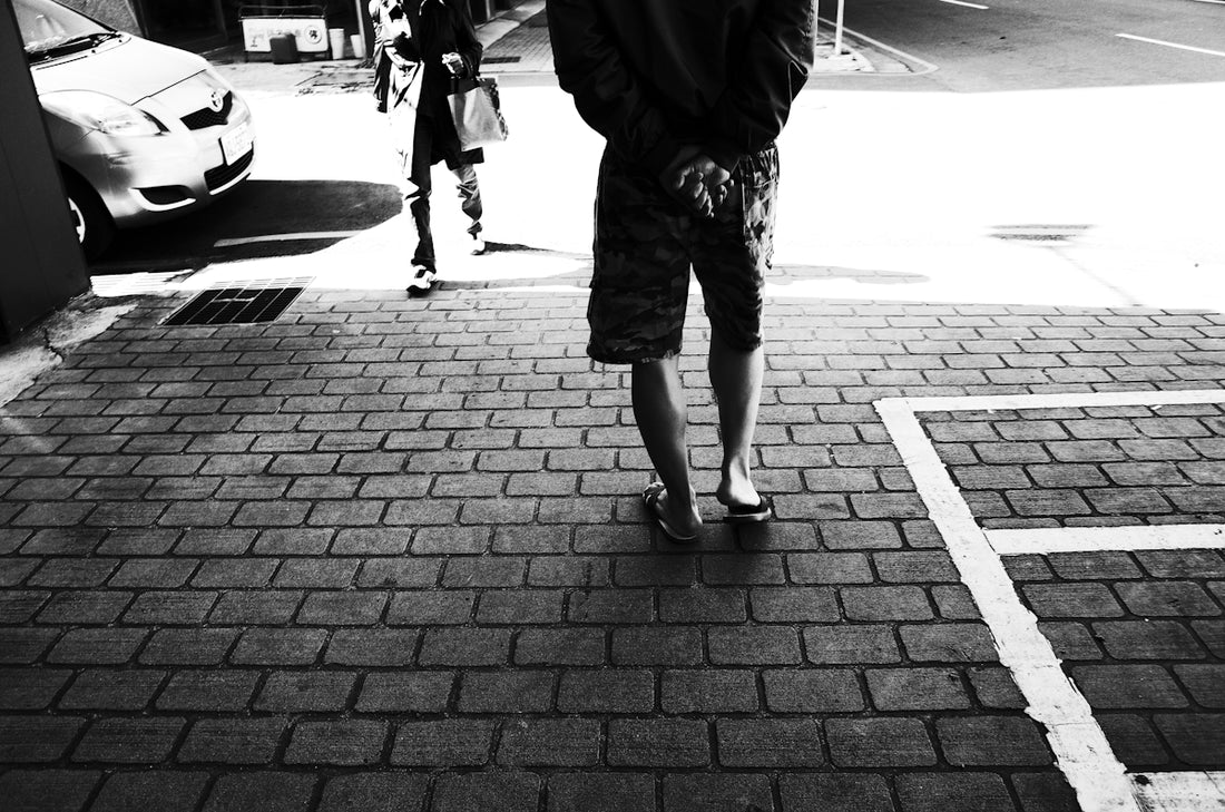 grayscale photo of woman walking on sidewalk