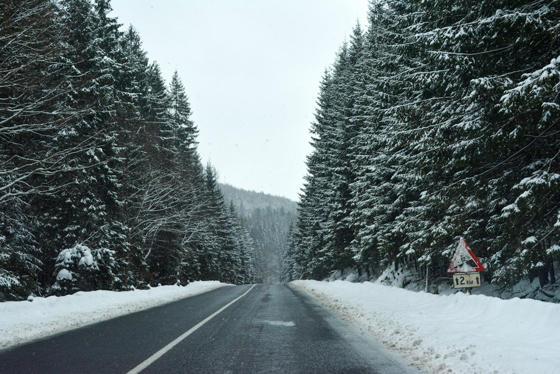 a snowy road with a sign on the side of it